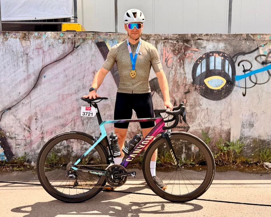Standing with the road bike and a finisher's medal